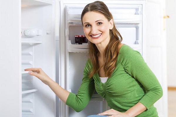 The process of washing the refrigerator A girl stands near the open refrigerator