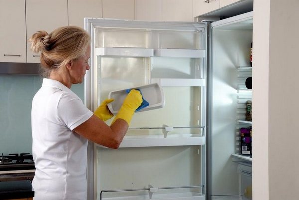 Cleaning process Woman washes a fridge