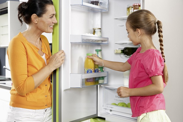 Choosing a refrigerator for home Woman and child at the open refrigerator