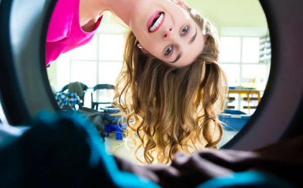 The girl looks into the hatch of the washing machine