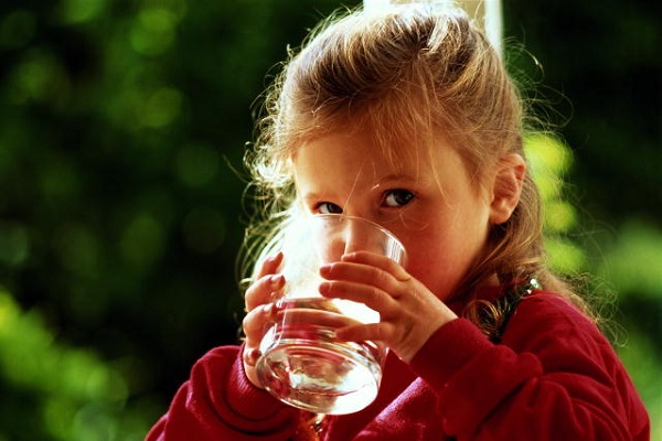 The child drinks water from a glass